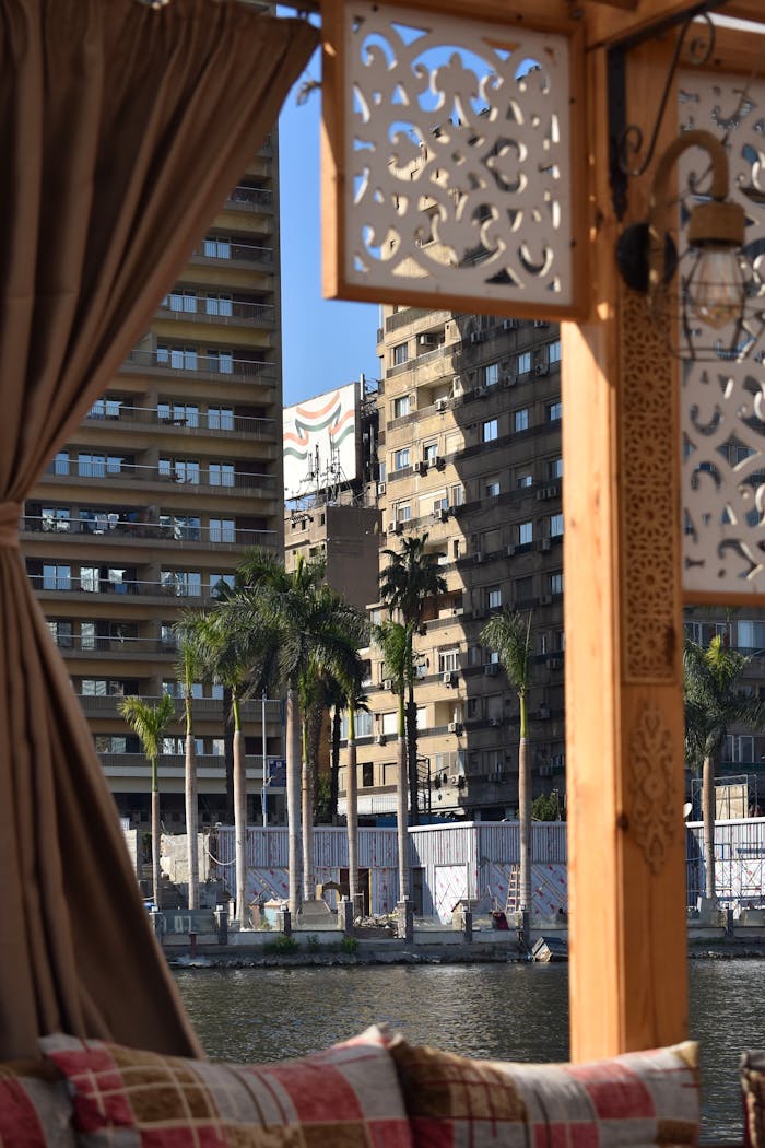 View from a boat on the Nile River overlooking Cairo's architecture and palm trees.